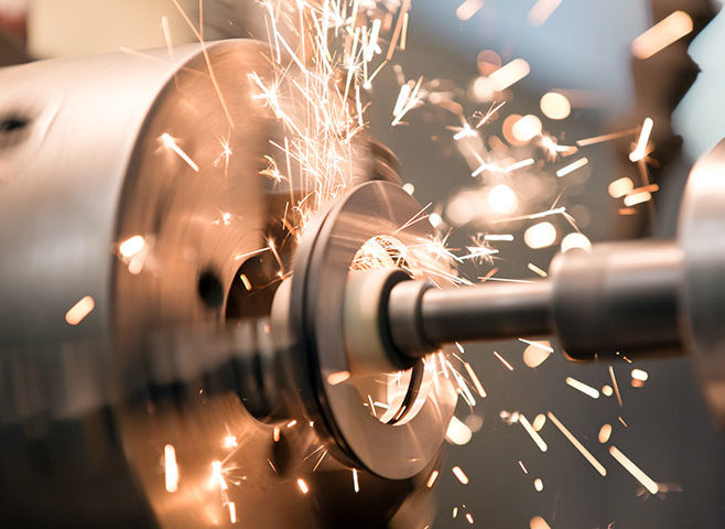 Metallschleifmaschine schleift Metall, Funken sprühen am Kontaktpunkt der rotierenden Teile, Nahaufnahme in Werkstatt.