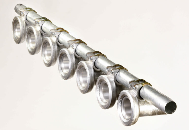 Acht Metallringe sind in einer Reihe mittels Klemmen an einer Metallstange befestigt, schräg auf weißem Grund liegend.