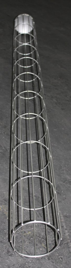 Langes zylindrisches Metallgitter mit gleichmäßig angeordneten Ringen liegt auf dunklem, strukturiertem Untergrund.